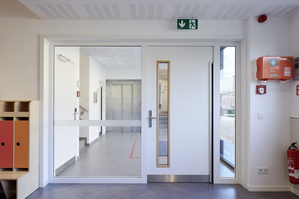 Sondertüren aus Alu in weiß. An beiden Seiten neben der Tür sind Fenster.