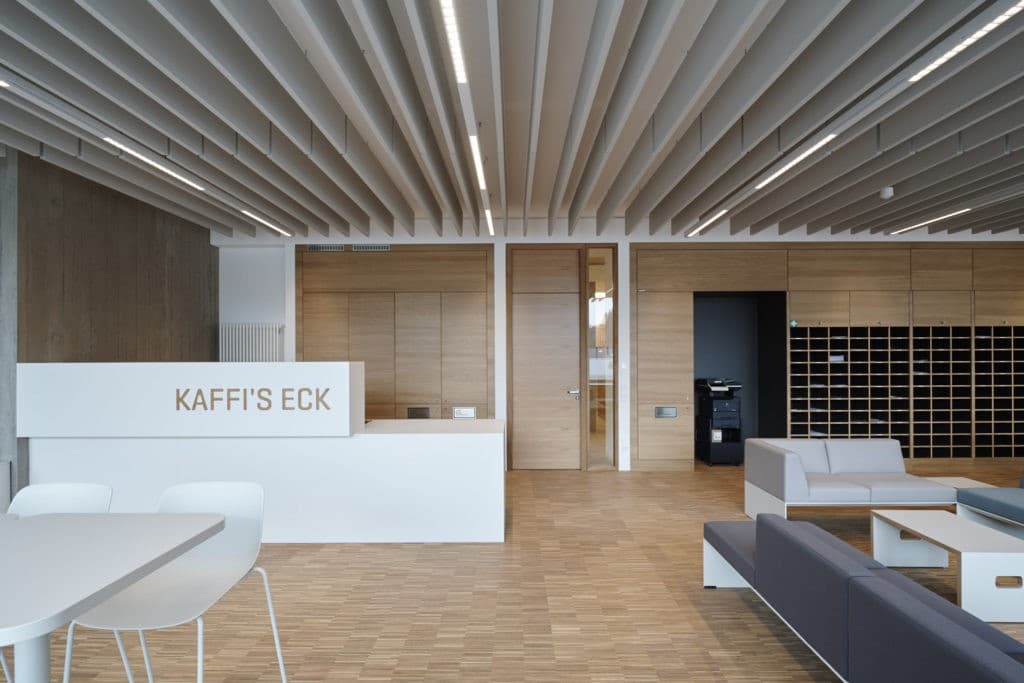 Großer Aufenthaltsraum mit weißer Holztheke, Boden mit Parkett verlegt.