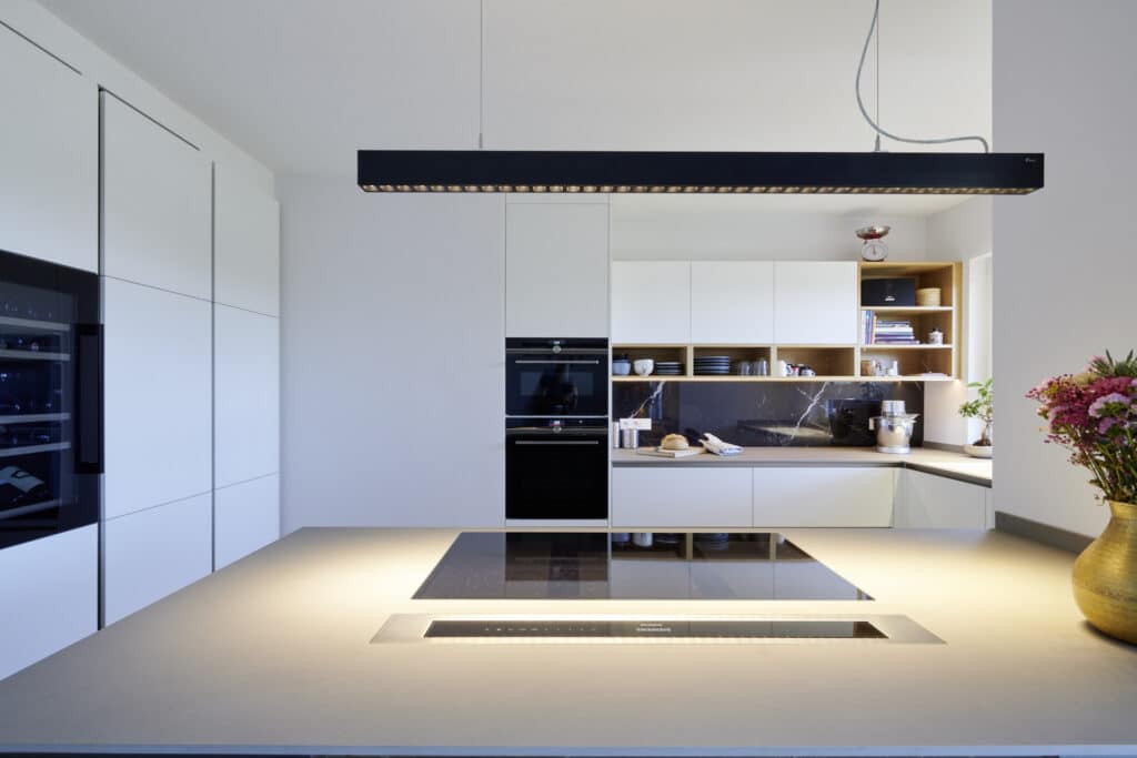 Vue d'ensemble d'une cuisine avec focalisation sur la plaque de cuisson. Cuisine blanche.