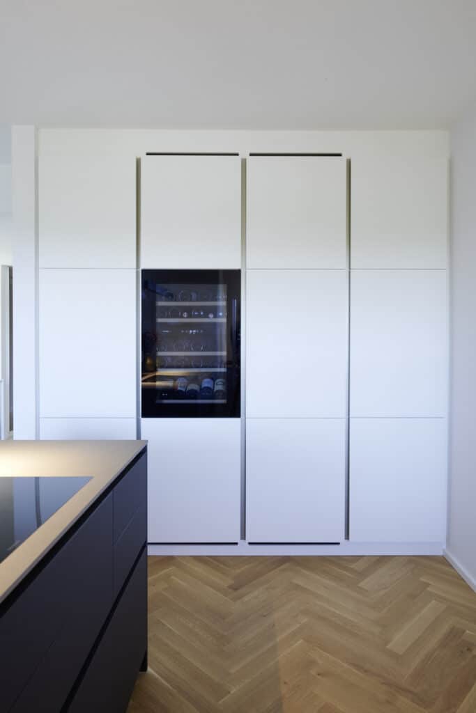 Gros plan sur un côté de la cuisine. Un mur avec des armoires et un réfrigérateur à vin.